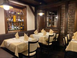 陶努斯山麓霍夫海姆波尔卡斯穆勒乡村酒店的一间设有白色桌椅的餐厅和一间酒吧