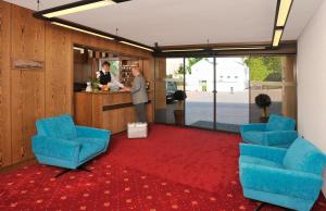 塞海姆-尤根海姆马辰加尼酒店的站在一个有蓝色椅子的房间的柜台上的人