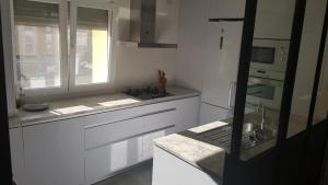 布尔戈斯Apartamento Vadillos - VuT 09-401的厨房配有白色橱柜、水槽和窗户。