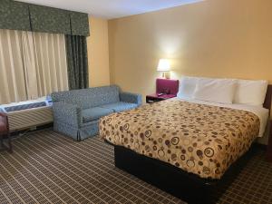 StewartvilleAmerica's Stay Inn Stewartville的配有一张床和一把椅子的酒店客房