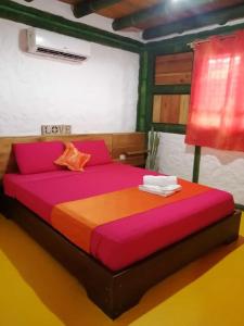 莫姆皮切Aparthotel Oleaje的一间卧室配有一张大床,配有粉色和橙色床单