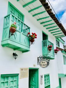 El CocuyHotel San Gabriel的白色的建筑,设有绿色的窗户和花盒