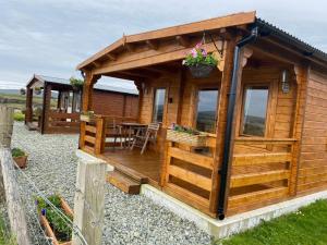邓韦根Harlosh Log Cabins的小木屋设有甲板和桌子