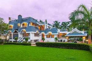 孟买Grey Mosaics by StayVista - Mountain-view villa in Vasai with Pool, Spacious lawn & Terrace的前面有绿色草坪的大房子
