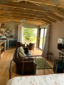 卡迪根Byre Cottages & Log Cabin的客厅设有真皮沙发和大窗户