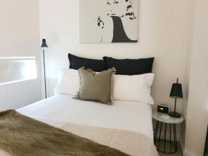 墨尔本达克兰海港避静公寓的一间卧室配有带白色床单和枕头的床。