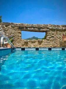 VillamielAqua Et Oleum的一座拥有石墙和蓝色海水的游泳池