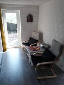 韦尔维耶Studio Au jardin fleuri的一间设有两把椅子和一张桌子的房间,以及一扇门