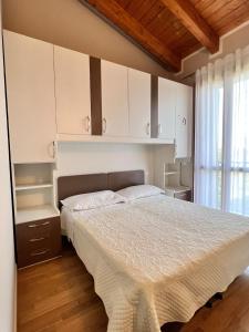 西尔米奥奈Appartamento Corina的一间卧室配有一张床、白色橱柜和窗户。