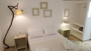 乌真托Dimora TerraNostra&Spa的卧室配有白色的床、两张桌子和一盏灯。