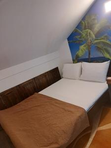 采蒂涅APARTMANI MIA VUKSANOVIC的墙上有棕榈树画的房间里一张床位