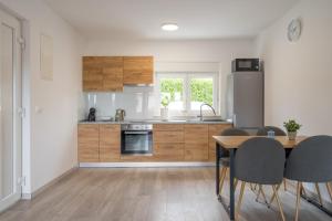 利纳迪奇Apartmani Villa Ruby的厨房配有木制橱柜和桌椅