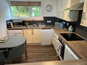 KensaleyreLoch Eyre Cottage的厨房配有白色橱柜、水槽和桌子