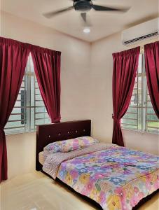 加央HOMESTAY BANDAR KANGAR (NS FAMILY HOMESTAY)的一间卧室配有一张带红色窗帘的床和风扇
