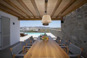 帕诺尔莫斯米科诺斯Summer Breeze Luxury Villa Mykonos的一间带木桌和椅子的用餐室