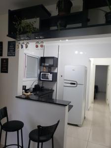 大普拉亚Apartamento beira-mar na praia da aviação的厨房配有柜台、两把椅子和一台冰箱