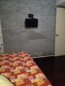 蒙得维的亚Aurora familiar的卧室配有1张床和1台砖墙电视