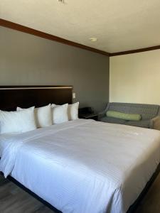 亨廷顿海滩亨廷顿海滩星光酒店的卧室配有一张白色大床和一把椅子