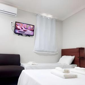 泰谢拉迪弗雷塔斯Pousada Avenida的客房设有两张床和一台墙上的电视。
