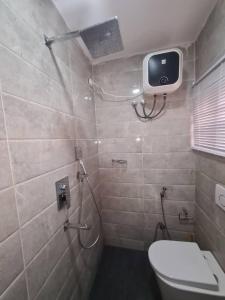 阿布贾Wine House, Maitama, Abuja的带淋浴和卫生间的浴室以及墙上的电视。