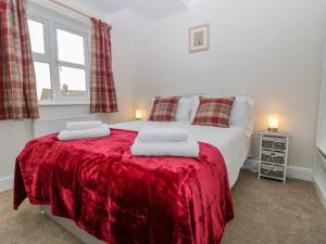 斯托昂泽沃尔德Woolpack Cottage的一间卧室配有一张带红色毯子的床