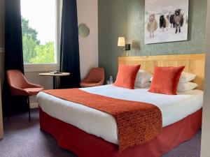 南特Hôtel Coeur De Loire的酒店客房配有一张带红色枕头的大床