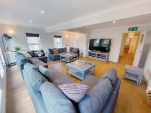 大雅茅斯Stunning 8-Bed House with Sea & Beach Views的客厅配有蓝色的沙发和电视