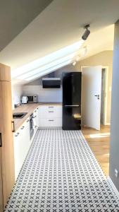 绿山城Drzewna Apartamenty -Augustowska的厨房配有黑色冰箱,铺有瓷砖地板。