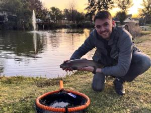 拉塞利亚拉塞利亚乡村庄园酒店的把鱼放在池塘旁的篮子里的人