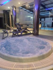 莱昂ARVA Spa París的一个带椅子的房间的热水浴缸和游泳池