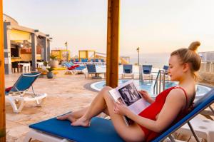 索瓦马皇冠广场约旦死海水疗度假酒店 的坐在沙滩椅上读书的女人