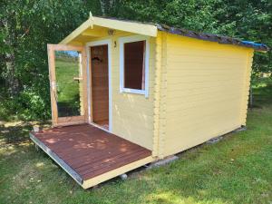 KiidjärveLõunamatkad的一座黄色的外屋,在院子里设有木甲板