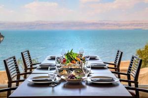 索瓦马皇冠广场约旦死海水疗度假酒店 的一张桌子,上面放着食物和酒杯,还有大海