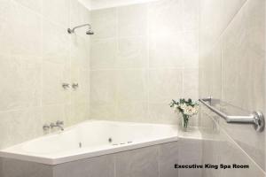 谭伯连山Mt Tamborine Stonehaven Boutique Hotel的白色的浴室设有浴缸和花瓶