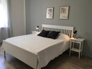 维罗纳Casa di Babi的卧室配有一张白色床,桌子上放着两盏灯