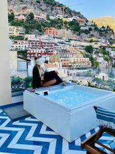 波西塔诺Villa Diamond Luxury Suite的坐在建筑物顶部浴缸中的女人
