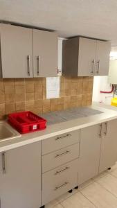 艾福雷诺德Vila Arthur的厨房配有白色橱柜和柜台上的红色托盘
