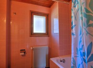 代堡Appartement Les Cascades的浴室铺有橙色瓷砖,设有窗户和浴缸。
