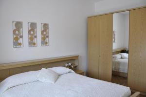 加尔达湖滨Appartamento Alba的卧室配有白色的床和镜子