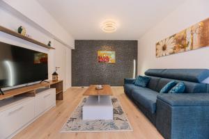 布拉索夫Luxury Landing Apartments Complex Qualis Brasov的客厅配有蓝色的沙发和平面电视。