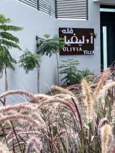 Al ‘AqarOlivia Chalet فلة أوليفيا的植物建筑的一侧的标志
