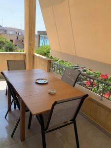 波多河丽Mimozas Apartment Porto Heli的鲜花阳台的木桌和椅子