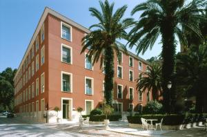 阿尔切纳巴尔尼尔里奥阿尔切纳莱昂 - 莱万特酒店的一座大型红色建筑,前面有棕榈树