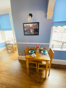 滨海韦斯顿All Seasons Bed & Breakfast - Adults Only的一间带木桌和椅子的用餐室