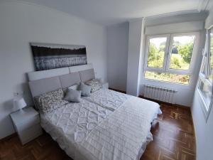 Posada de LlanesApartamento MAR y MONTAÑA ASTURIAS的卧室配有白色的床和2扇窗户。
