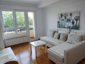 Posada de LlanesApartamento MAR y MONTAÑA ASTURIAS的客厅配有白色沙发和2扇窗户。