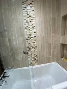 博尔顿Comfortably furnished 2 bedroom home in Bolton的设有带白色浴缸的淋浴的浴室