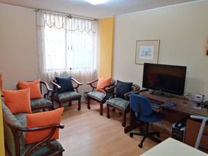 基多Hermoso Apartamento al Norte cerca de la Embajada Americana的客厅配有椅子和一张书桌及电视