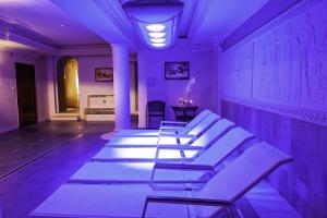 华沙阿卡迪亚皇家酒店 的紫色灯光的房间的一排白色椅子