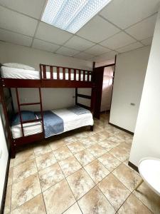 圣何塞Hermoso apartamento en la capital de Costa Rica的客房设有两张双层床,铺有瓷砖地板。